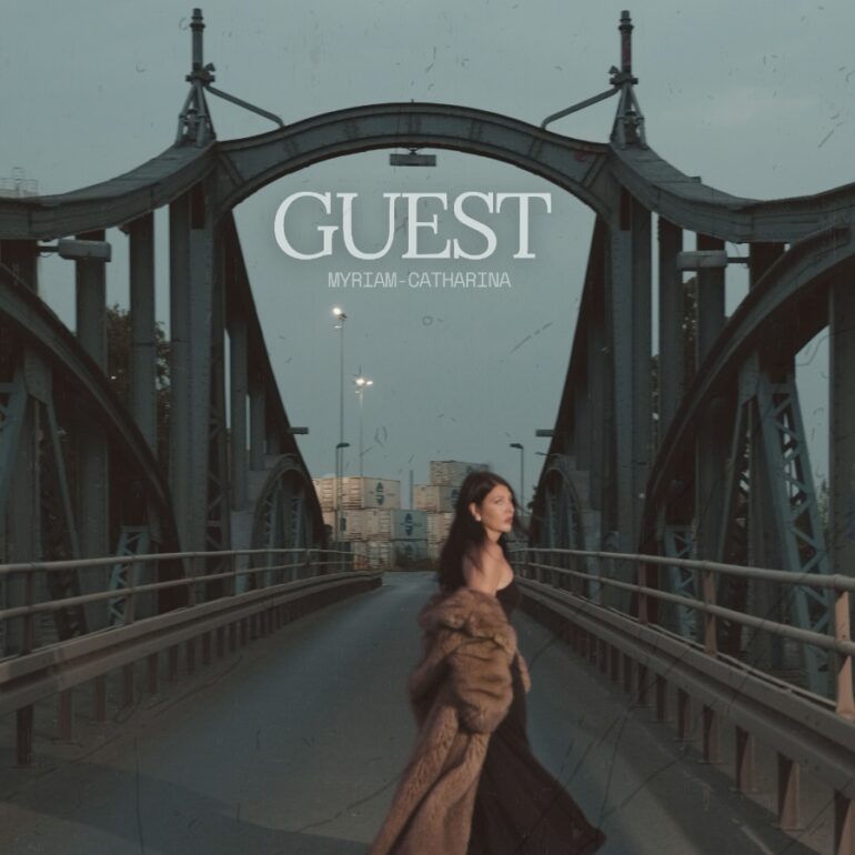Sängerin Myriam-Catharina mit Kleid und Mantel nachts auf einer Brücke (Cover Song "Guest")